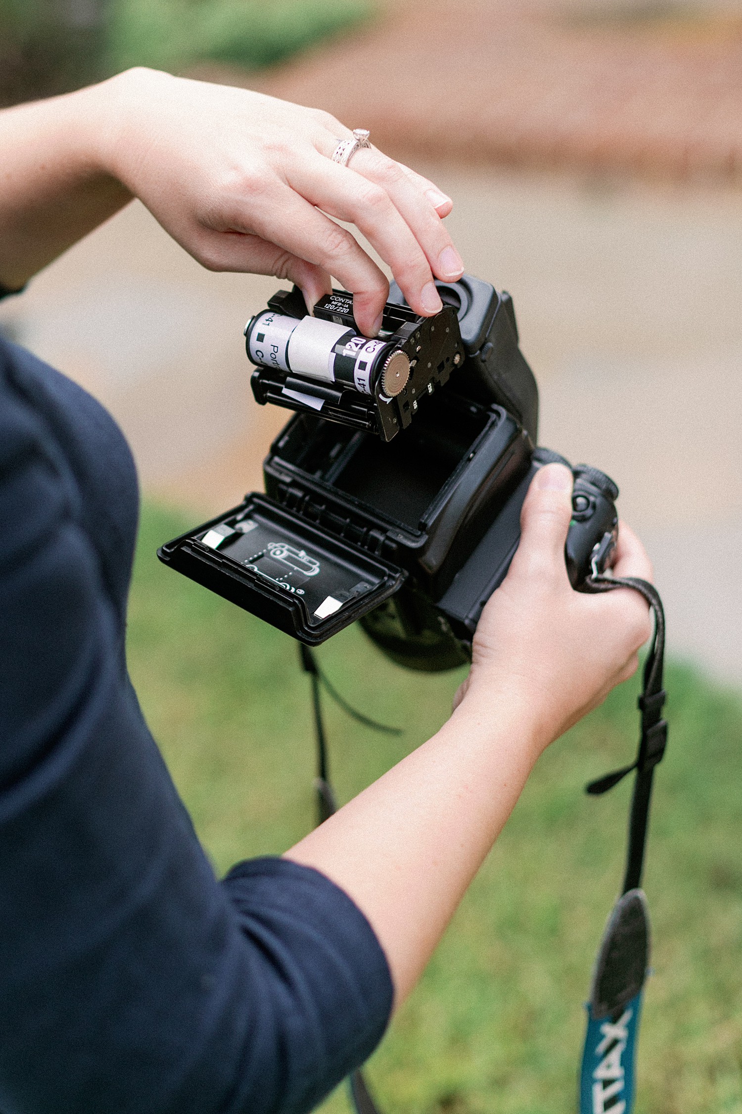 A female photographer inserts film into her analogue camera as she prepares to talk about What is Film Photography? Image by Victoria Heer, a Washington DC wedding photographer.