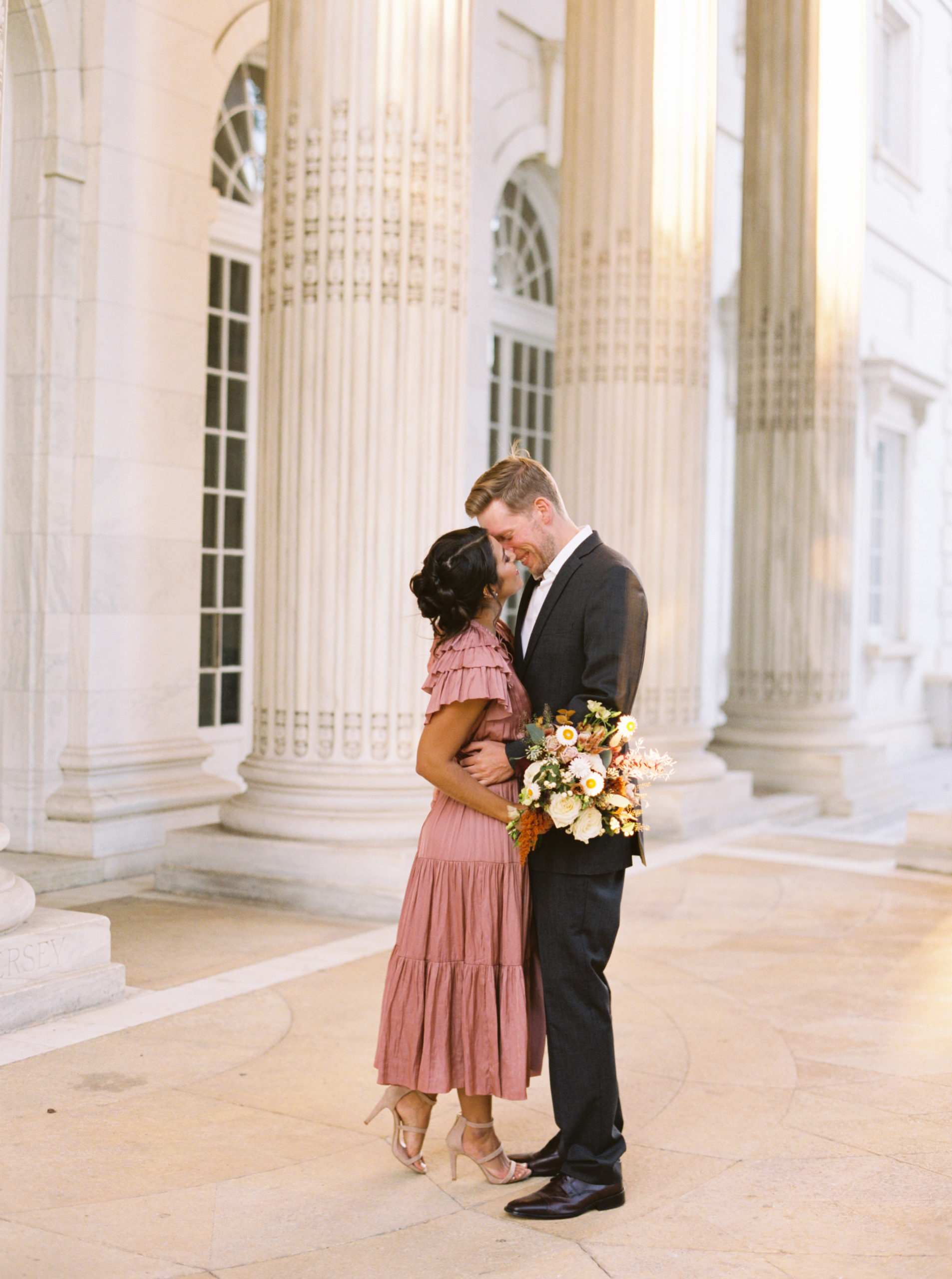 Groom to be kisses bride to be on her forehead as they celebrate their engagement session at at the Daughters of the American Revolution in Washington, DC photographed by Victoria Heer, luxury wedding photographer.