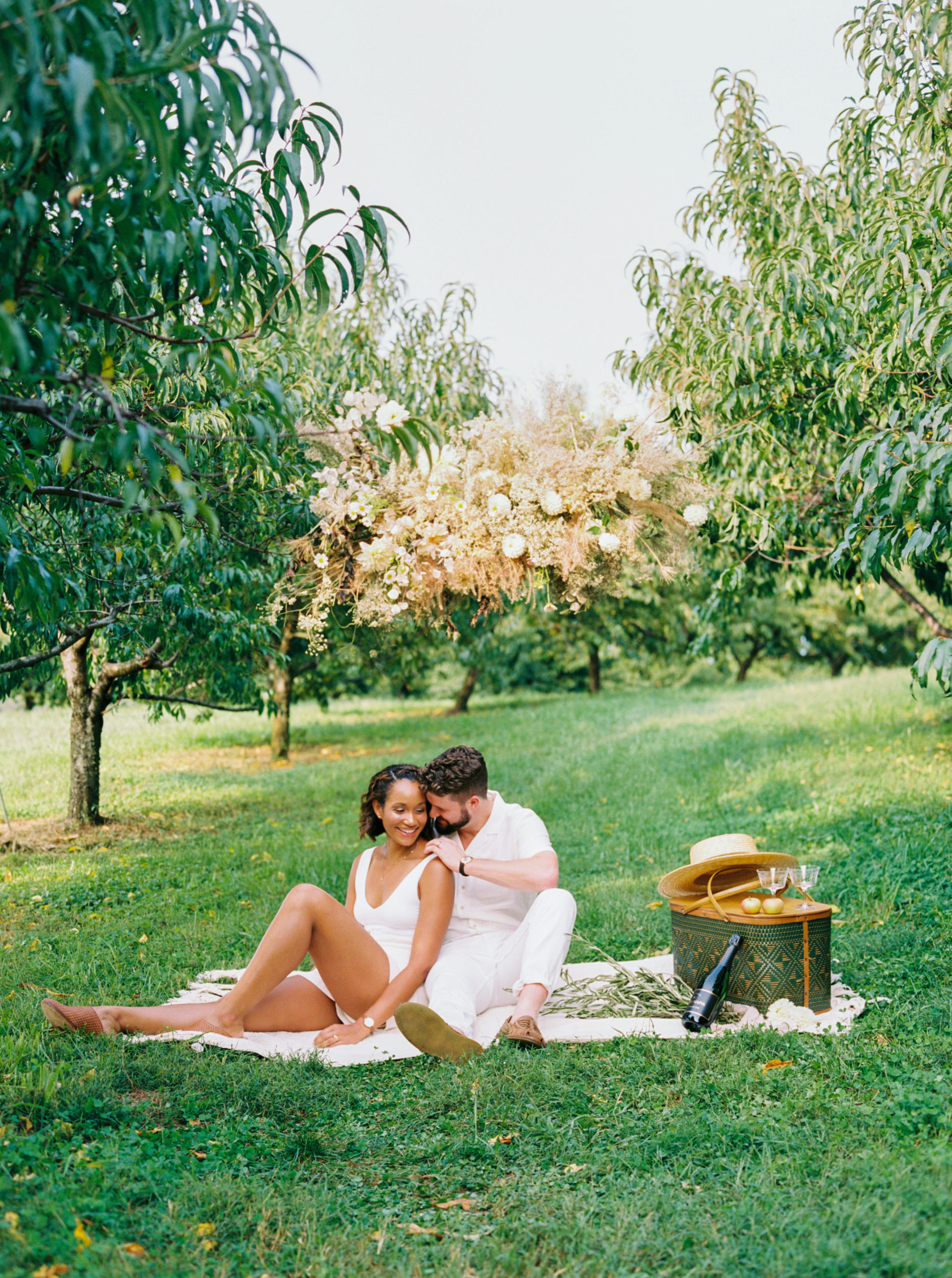A man leans over to kiss his wife while they sit on a picnic blanket during their The Market at Grelen Anniversary Photo Shoot. Image by Victoria Heer, Washington DC wedding photographer.